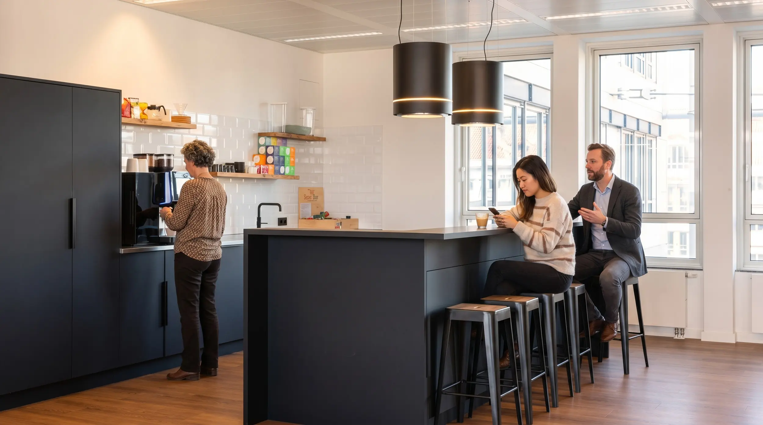 Mitarbeiter nutzen Office-Kaffeeküche mit Theke, Sitzplätzen und Kaffeemaschine.
