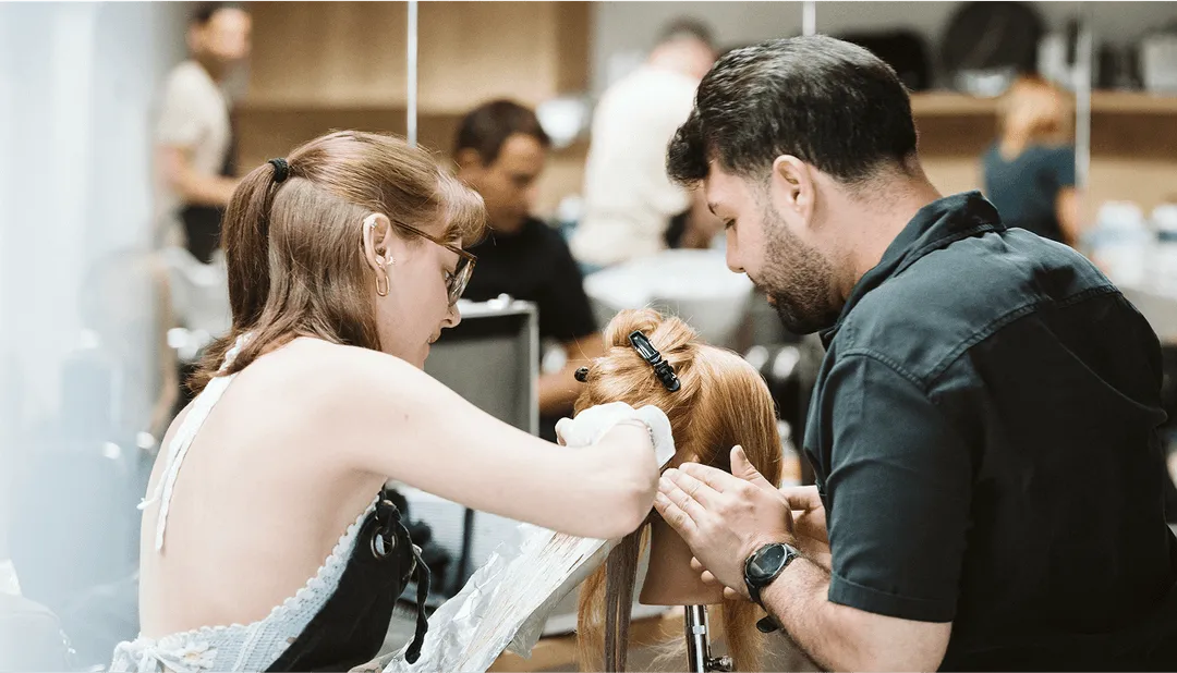 Friseure färben Haare an Puppe, fokussierte Arbeit in modernem Salon. Professioneller Umgang mit Blondtönen.