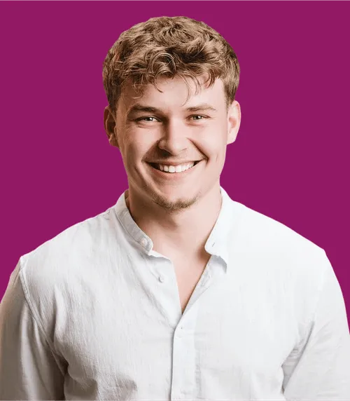 Lächelnder Mann in weißem Hemd vor lila Hintergrund.