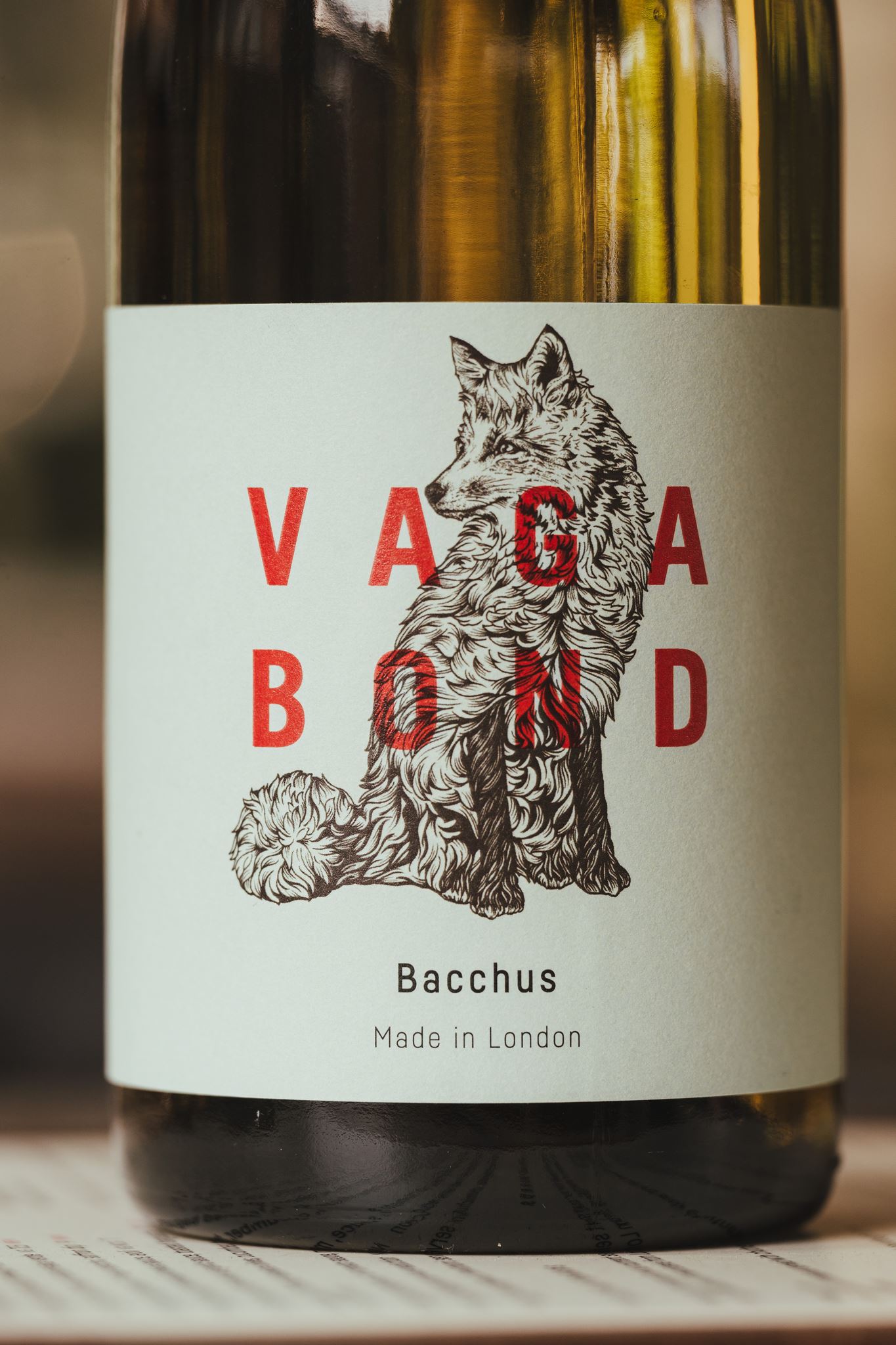 Wine bottle label with red letters spelling Vagabond over a detailed sketch of a seated fox.