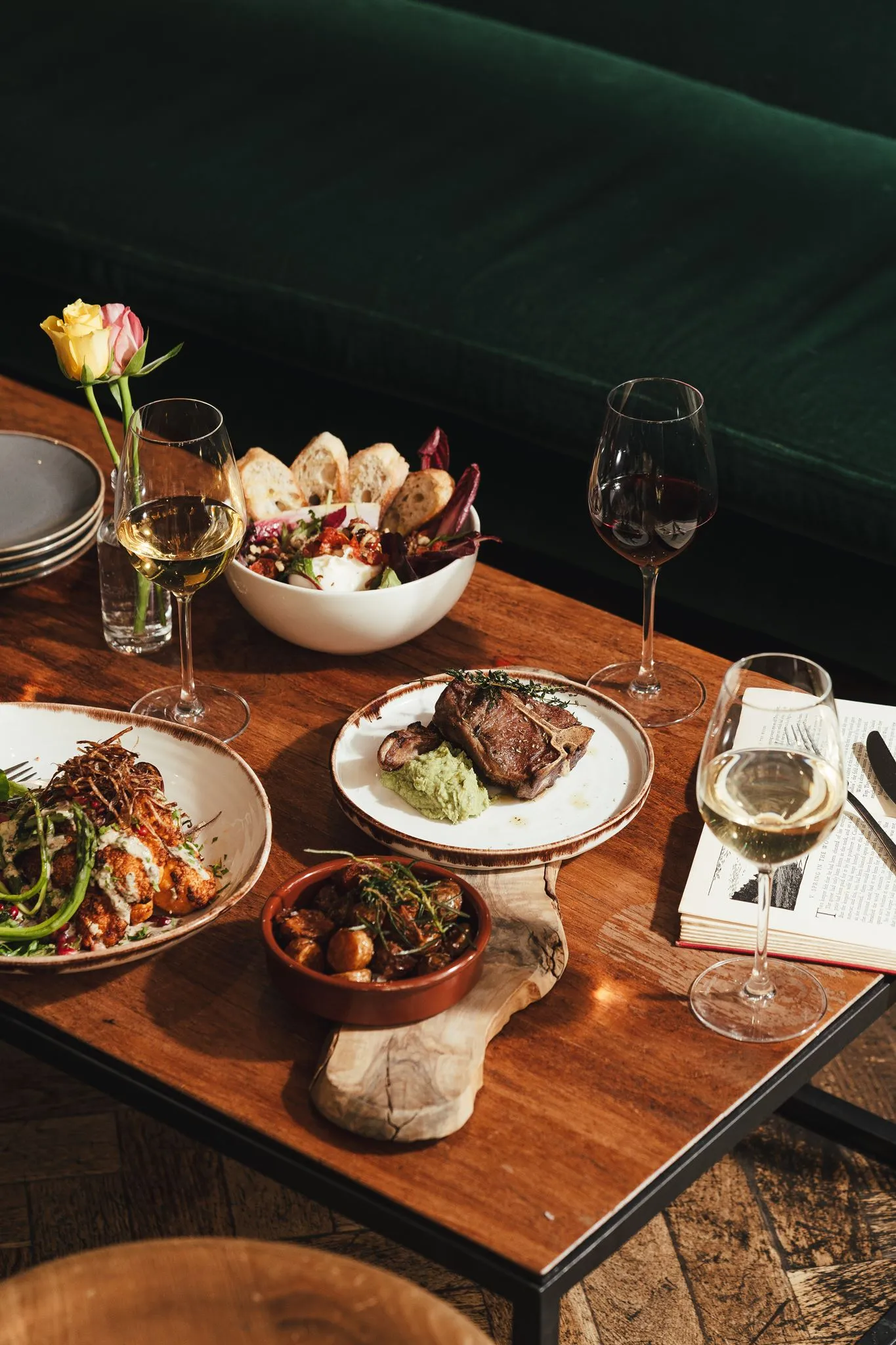 Sharing plates of charcuterie, salad and roast potatoes with glasses of red and white wine