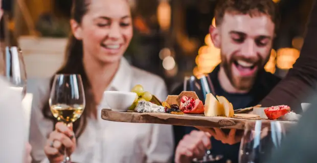 Guests with glasses of white wine sharing a board of cheese and fruit at a Vagabond cheese and wine masterclass