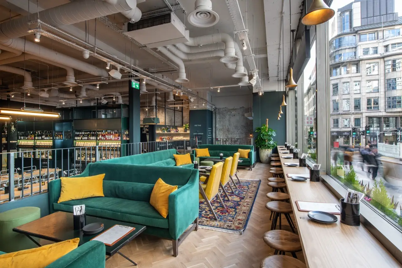 Green velvet sofas with mustard cushions and window bar seating at Vagabond Monument in the City of London