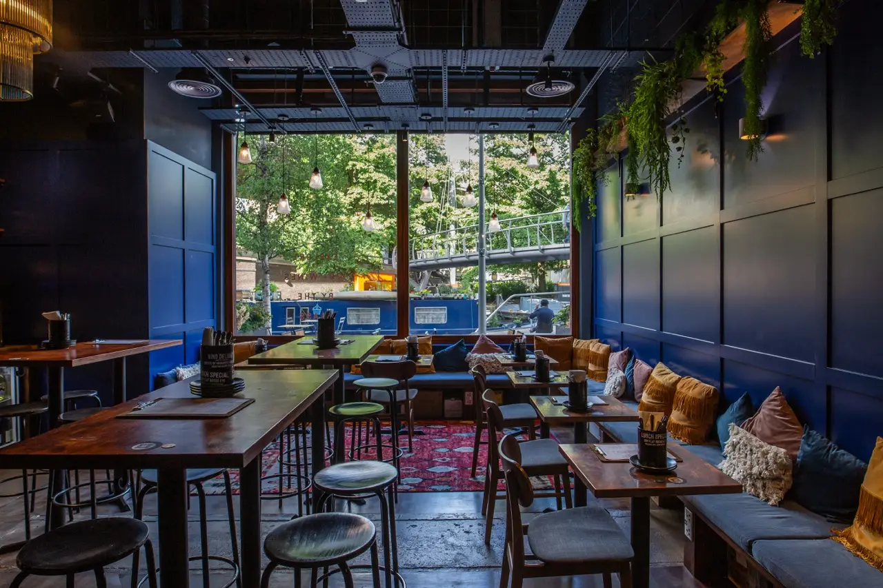 Navy-panelled bar with cushioned banquettes and windows onto the canal at Vagabond Paddington