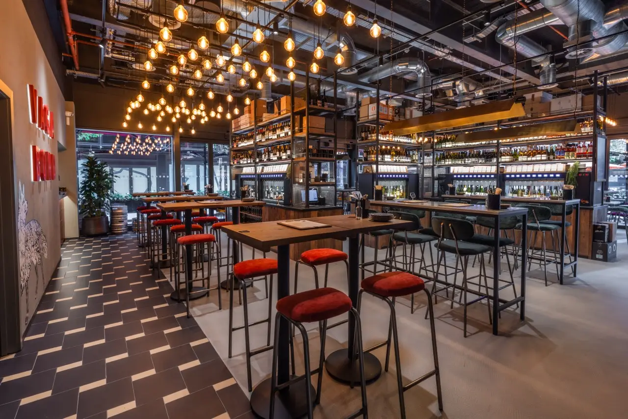 High tables with red stools under hundreds of hanging bulbs at Vagabond Liverpool Street