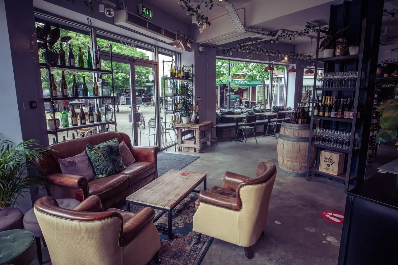 Leather sofas and armchairs in the lounge area at Vagabond Fulham, with open doors onto the street