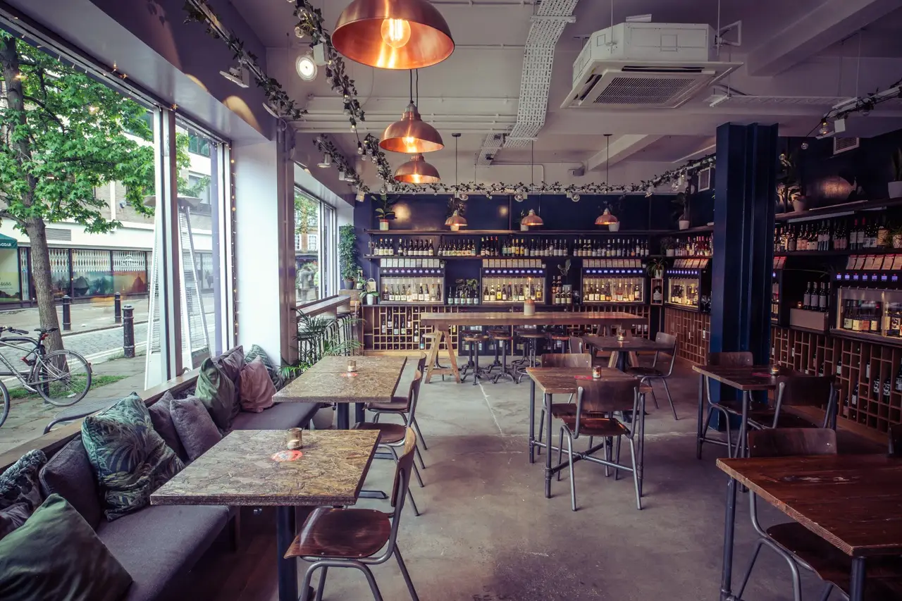 Window seating with cushioned banquettes and copper pendant lights at Vagabond Fulham