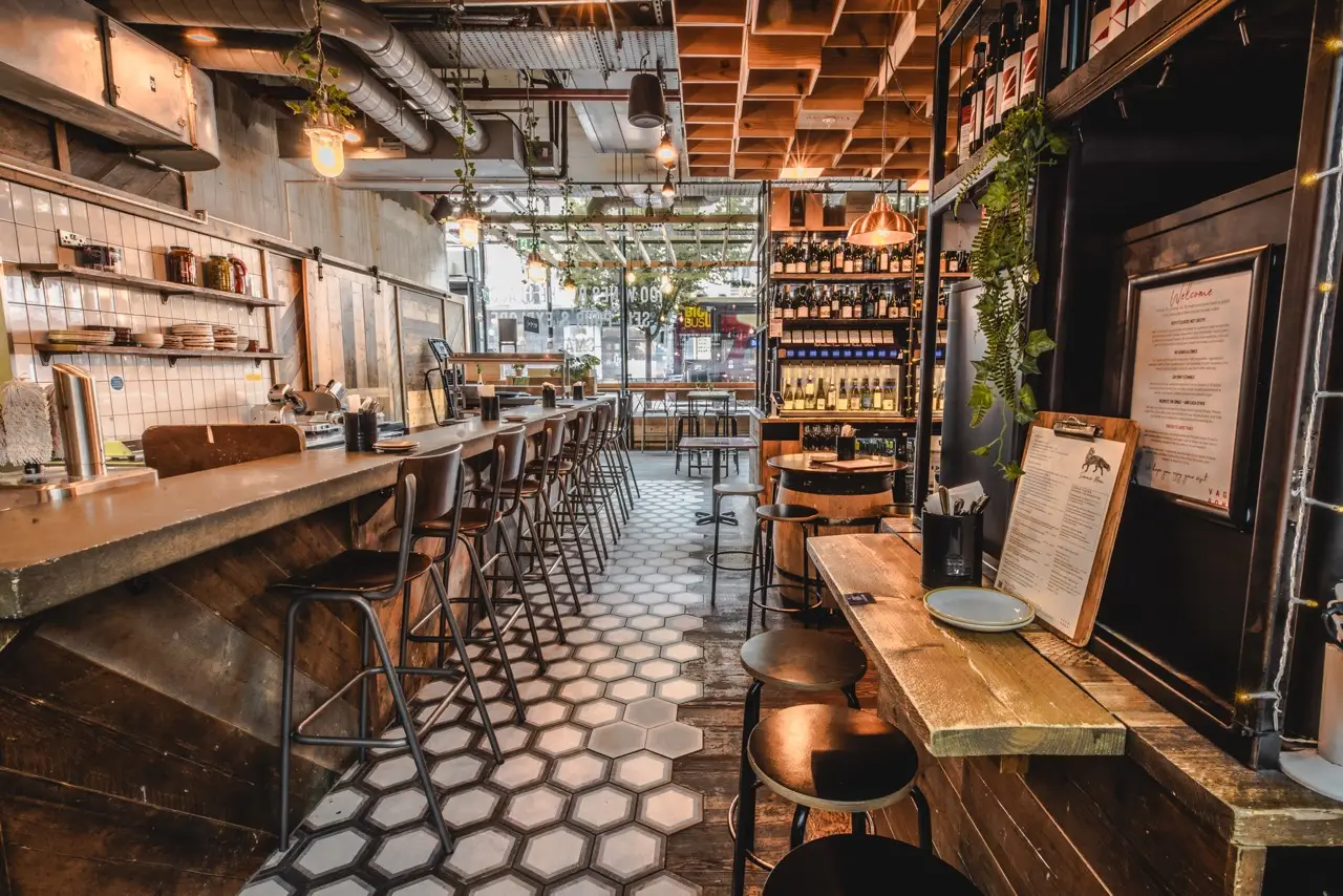 Concrete-topped bar with high stools on a hexagonal tiled floor at Vagabond Victoria
