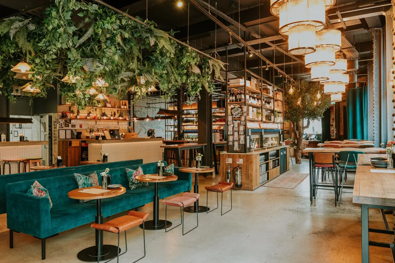 Teal velvet banquettes, hanging plants and tiered chandeliers inside Vagabond Birmingham on Colmore Row