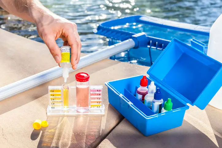 Pool technician testing water chemistry with a chlorine and pH testing kit