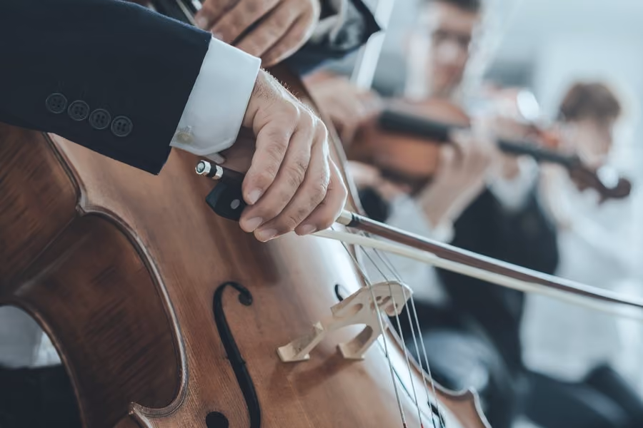 Detail rukou hudebníka se smyčcem na violoncellu v orchestru