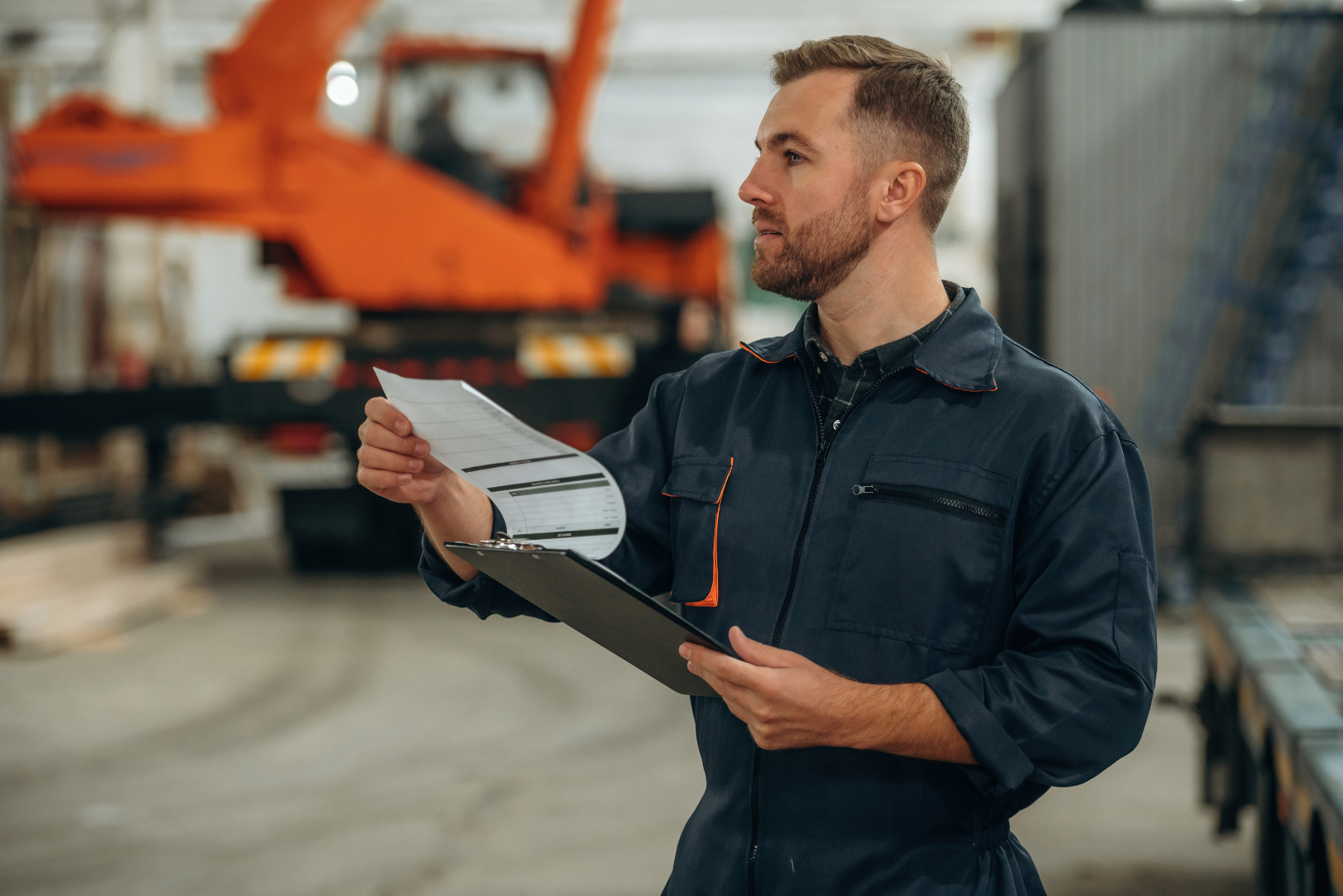 Factory worker checking delivery document on clipboard during manufacturing operations