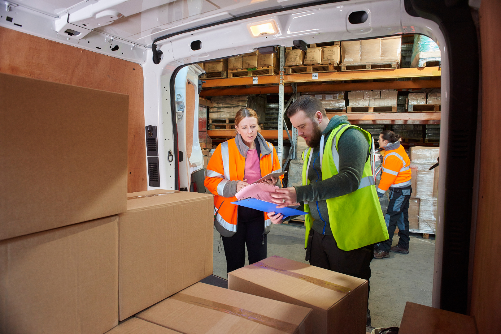 Warehouse staff reviewing shipping documents during goods delivery in manufacturing logistics
