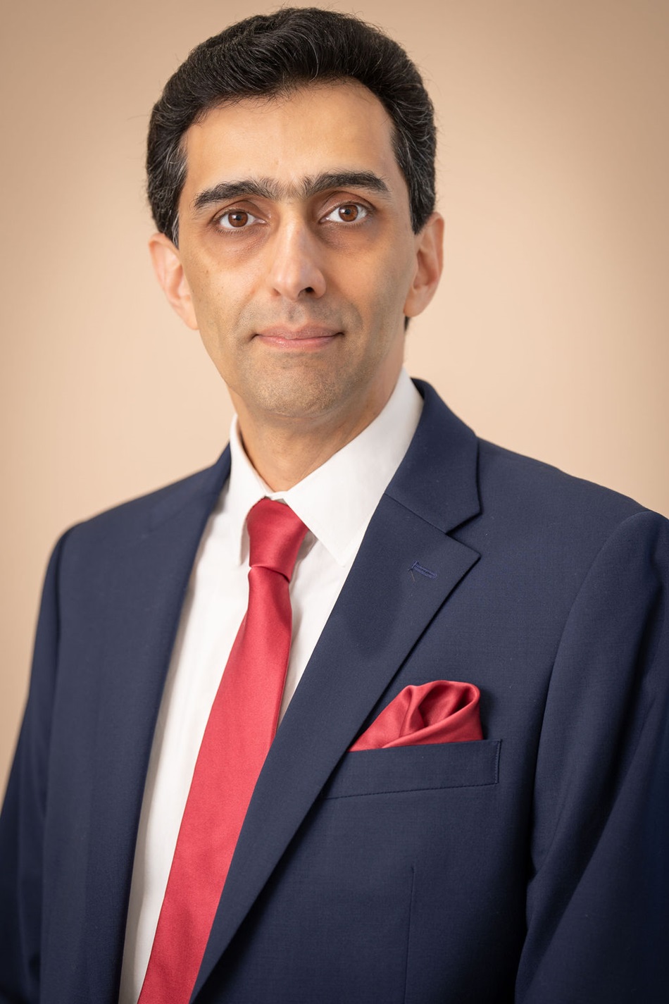 Sam Agdasi wearing navy suit red tie and pocket square
