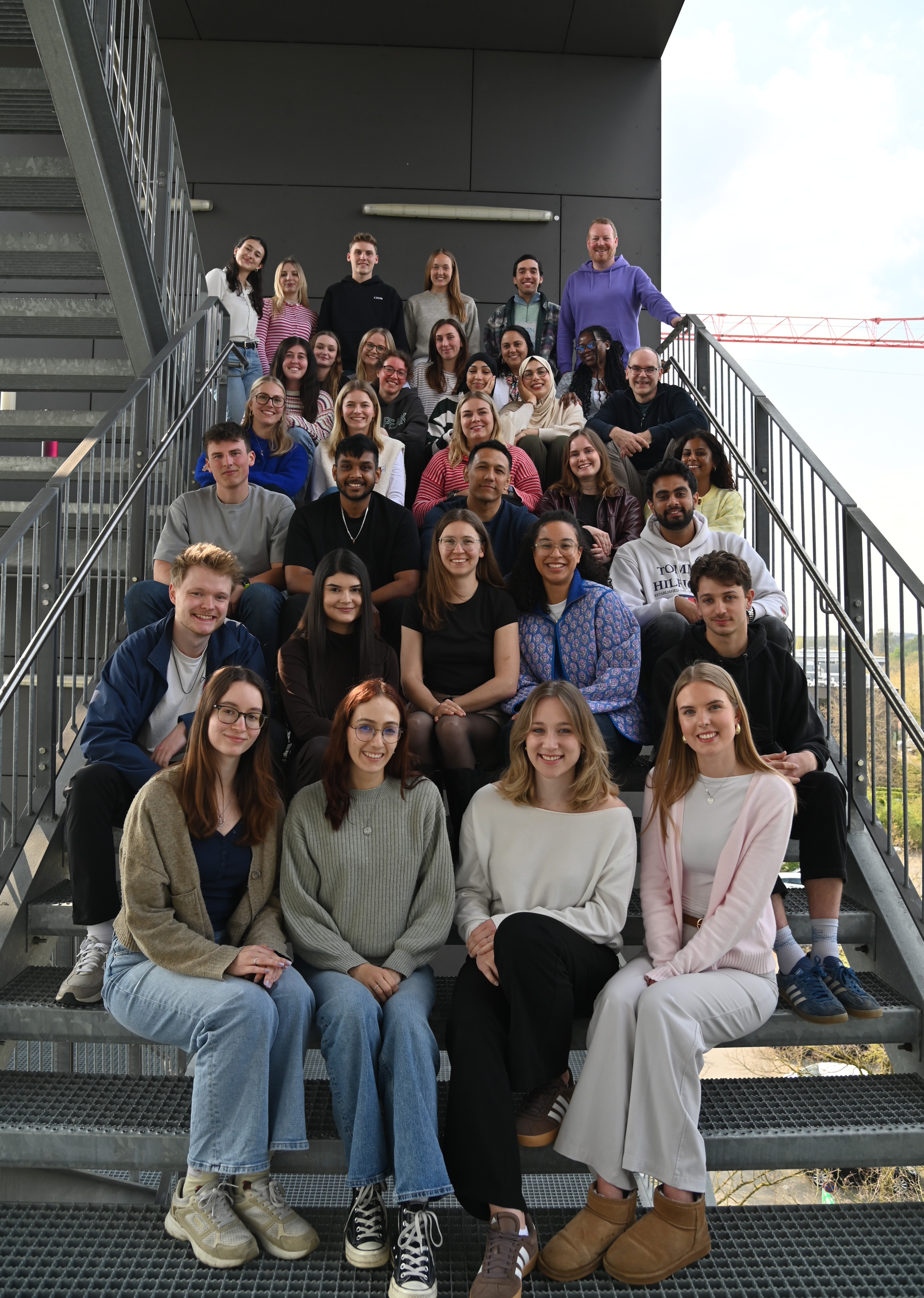 Class of IMS Students and Professors  sitting on the stairs at the FH Building
