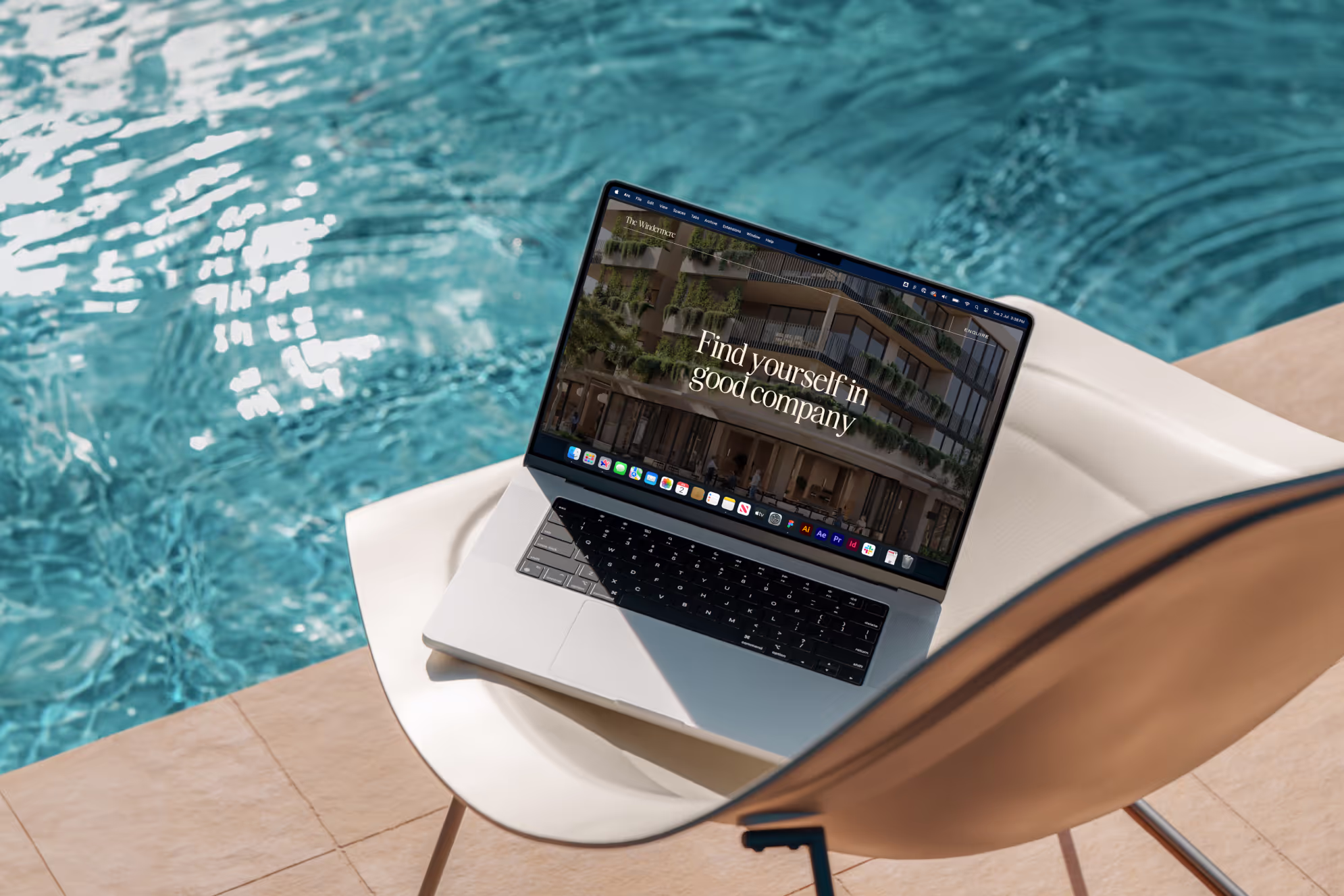 Open laptop on white chair beside a pool showing a webpage with text 'Find yourself in good company'.
