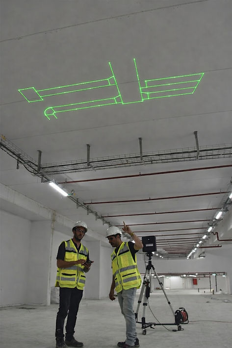Two construction workers using laser projection to display BIM model ductwork geometry on a ceiling, showing exact HVAC layout positions during field installation