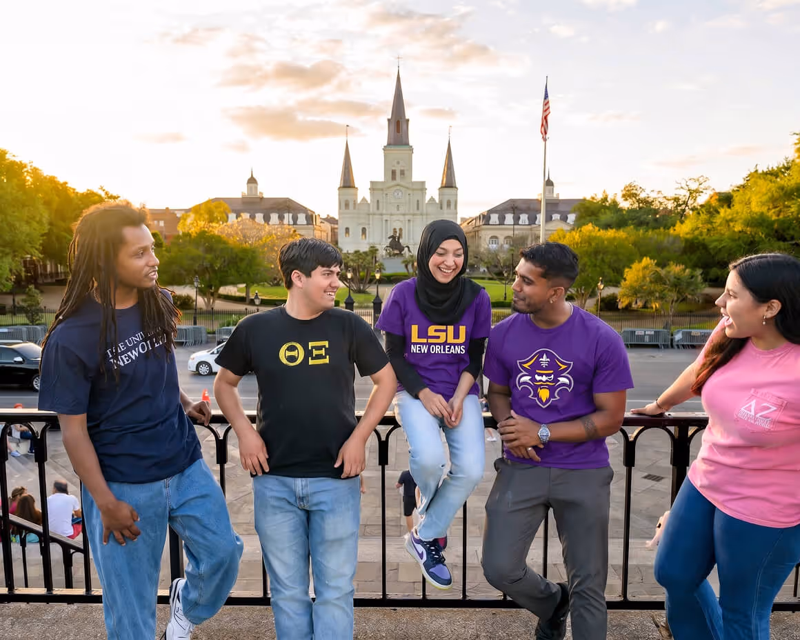 Five diverse college students in LSU shirts talking with cathedral and American flag in background.