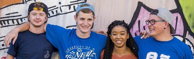4 LSU New Orleans Students, arms around each other, smiling for a group photo