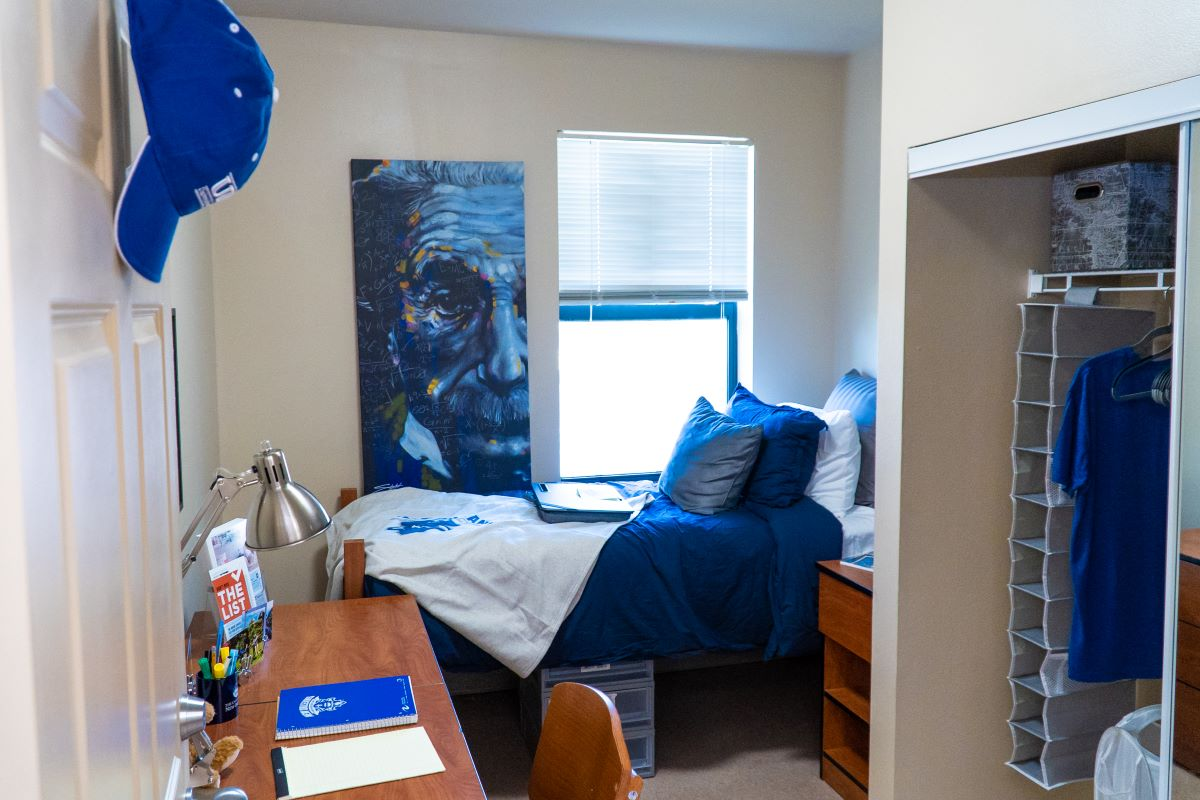 Image of interior of Pontchartrain Hall bedroom with bed and desk filled with LSU New Orleans memorabilia. 