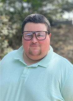 Kent Giblin. Man with short dark hair and glasses wearing a light blue collared shirt outdoors.