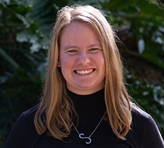 Samantha Broussard. Smiling woman with long blonde hair wearing a black top and silver necklace outdoors.