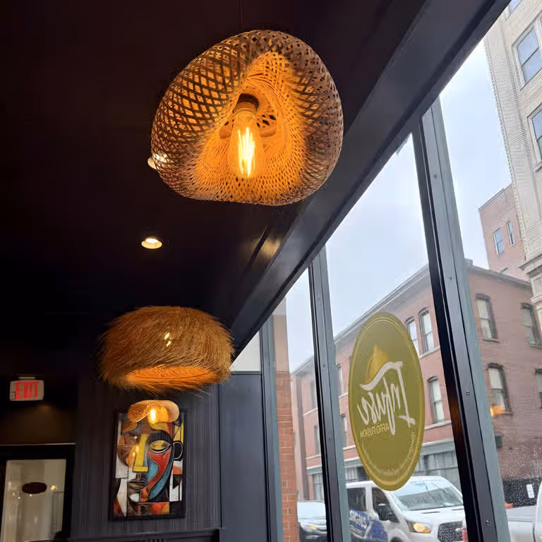 Decorative hanging lamps and a colorful abstract face painting inside a cafe by large windows.