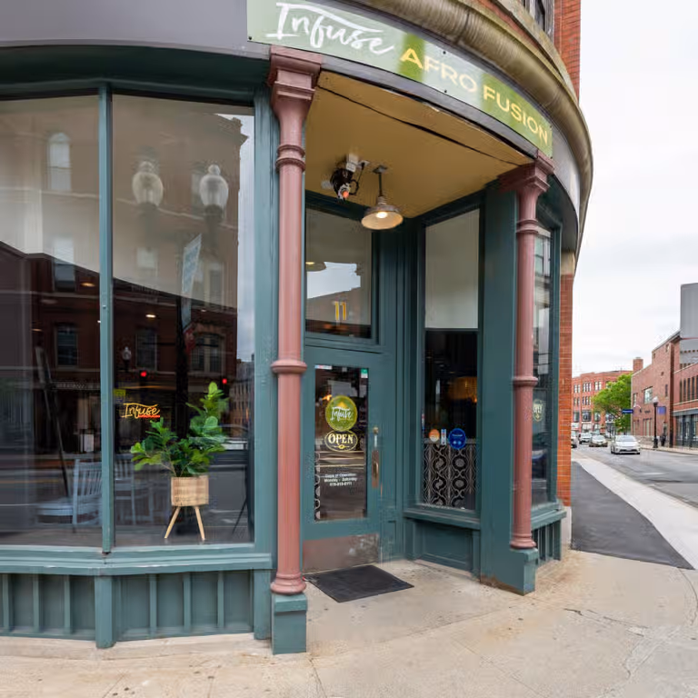 Corner entrance of Infuse Afro Fusion restaurant with green framed windows and door, and street view.