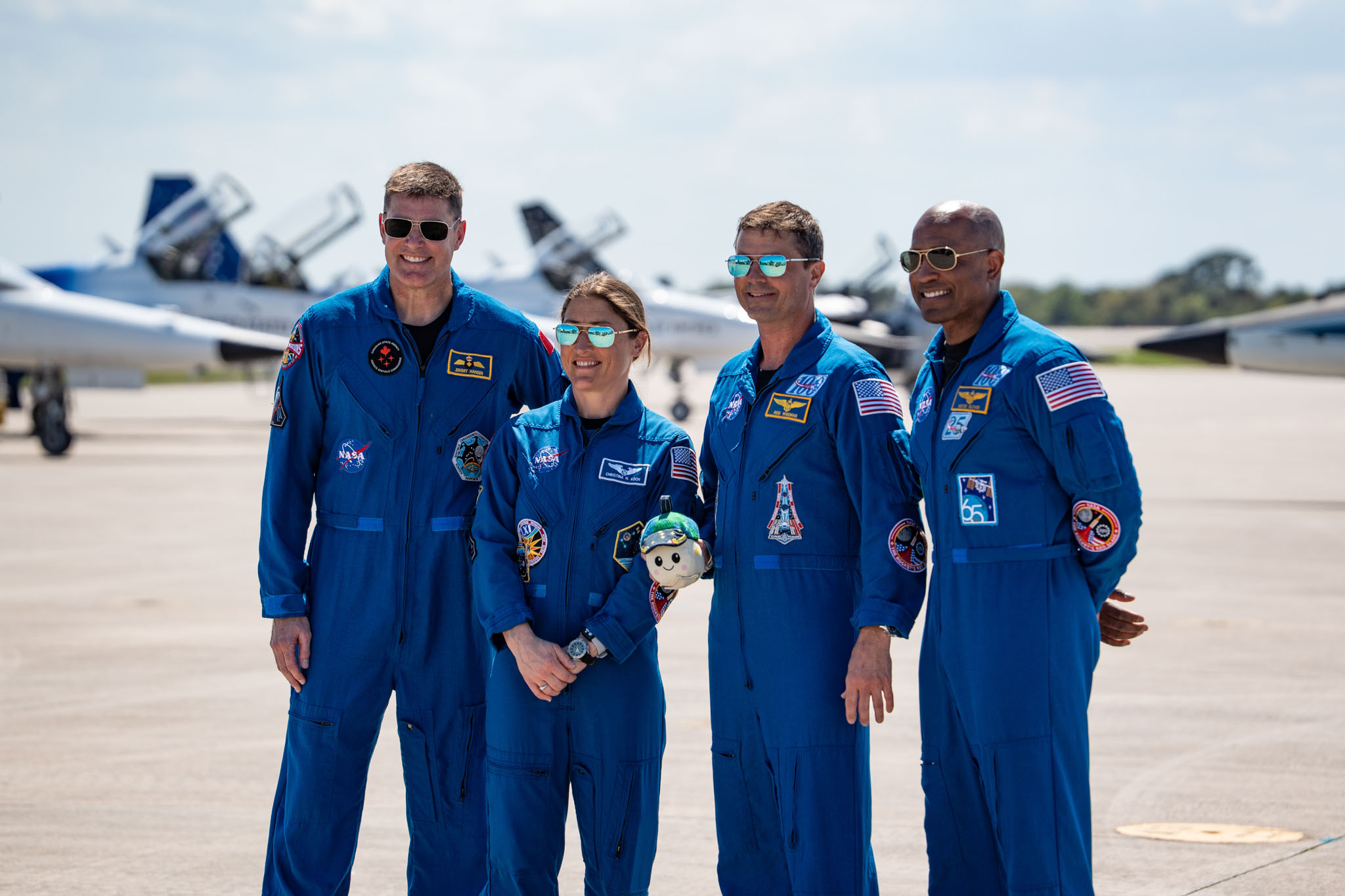 Artemis 2 crew members posing in blue flight suits on a runway at Kennedy Space Center