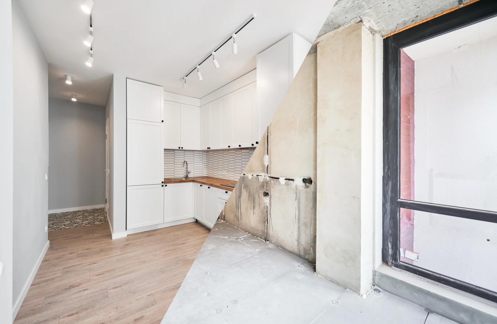 Halb renovierte Küche mit modernen weißen Schränken und alte, unrenovierte Wand mit Fenster.