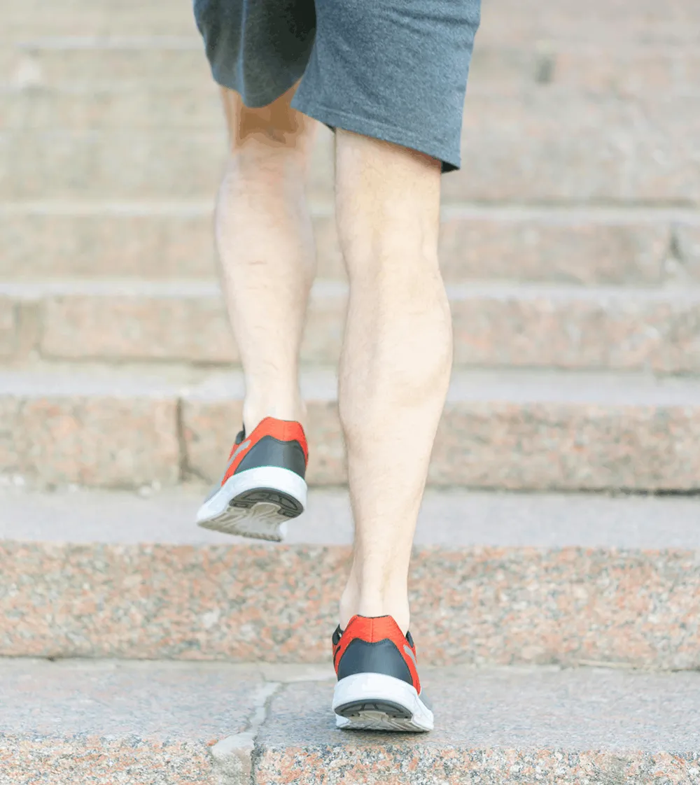 A person walking up outdoor steps wearing sneakers and shorts, illustrating the improved mobility and faster recovery patients experience following minimally invasive knee replacement surgery.