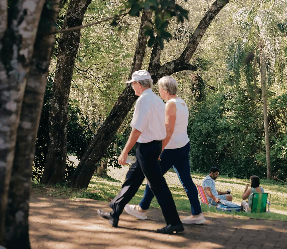 An older couple walking together outdoors on a sunny day, illustrating the improved quality of life and active lifestyle possible after total or partial knee replacement surgery with Dr. Jeffrey A. Geller MD.