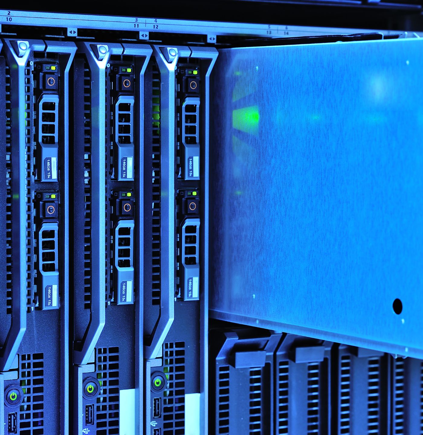 Close-up of multiple server rack units with illuminated power buttons and network ports in a data center.