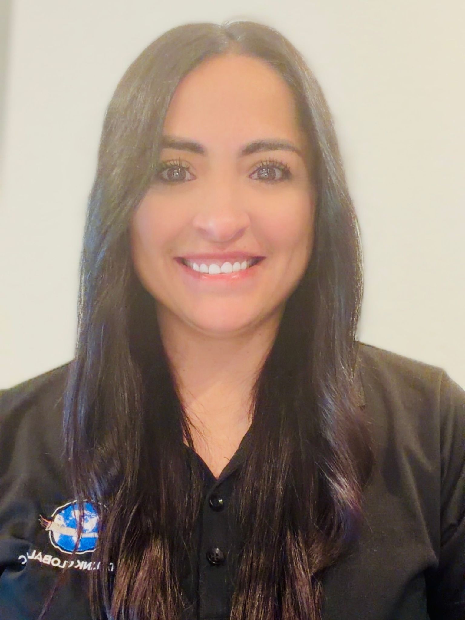 Smiling woman with long dark hair wearing a black collared shirt with a company logo.