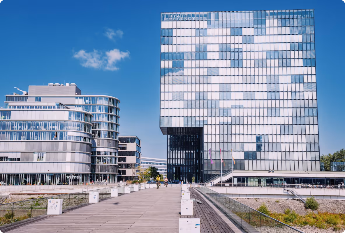 Modernes Hyatt Regency Hotelgebäude mit Glasfassade neben einem runden Bürogebäude unter blauem Himmel.