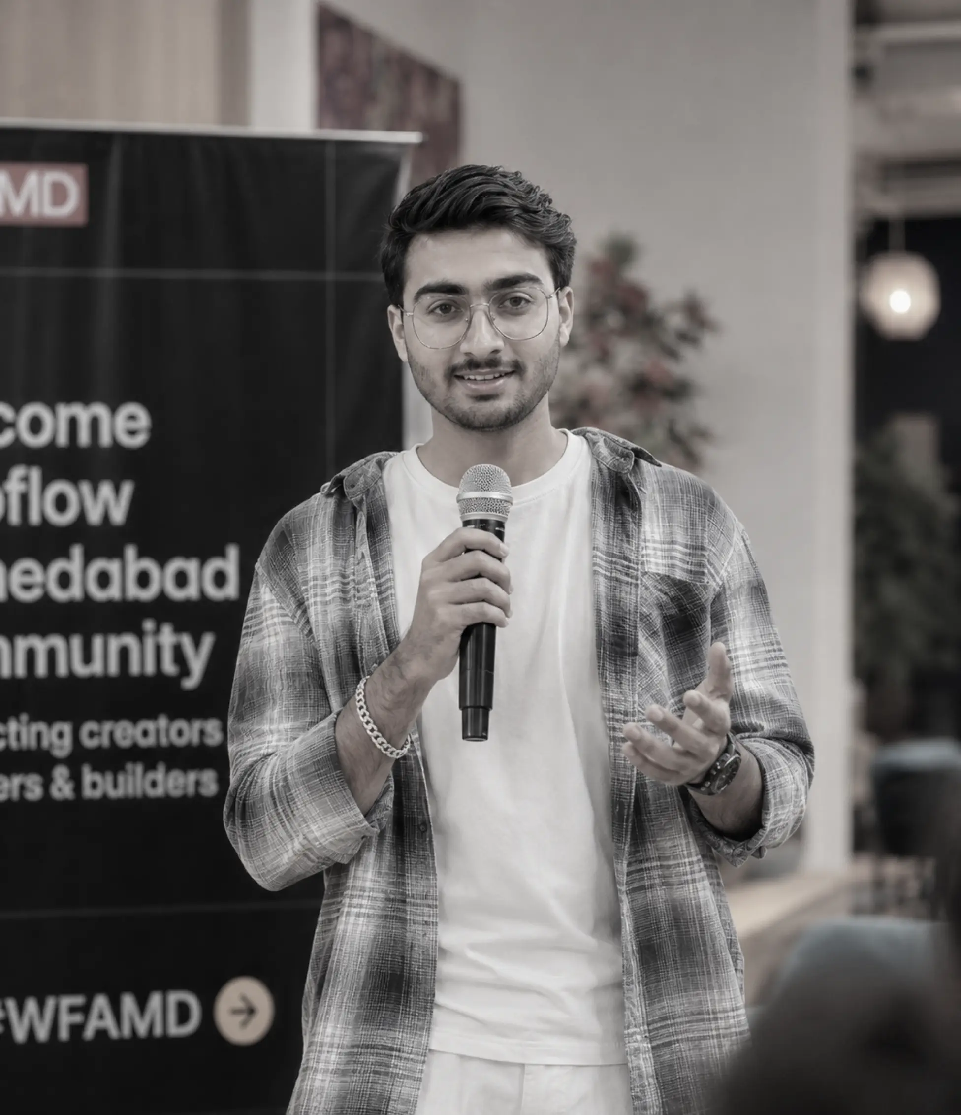 Young man in a white shirt with arms crossed smiling in front of a wall with text.