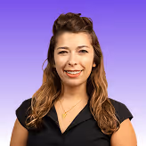 Smiling woman with wavy brown hair wearing a black top against a purple gradient background.