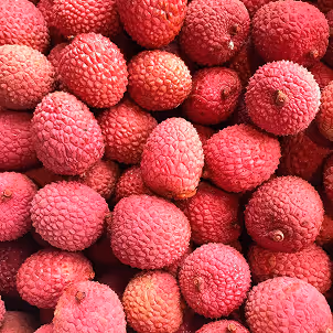 Close-up of a pile of ripe lychee fruits with rough, bright pinkish-red textured skin.