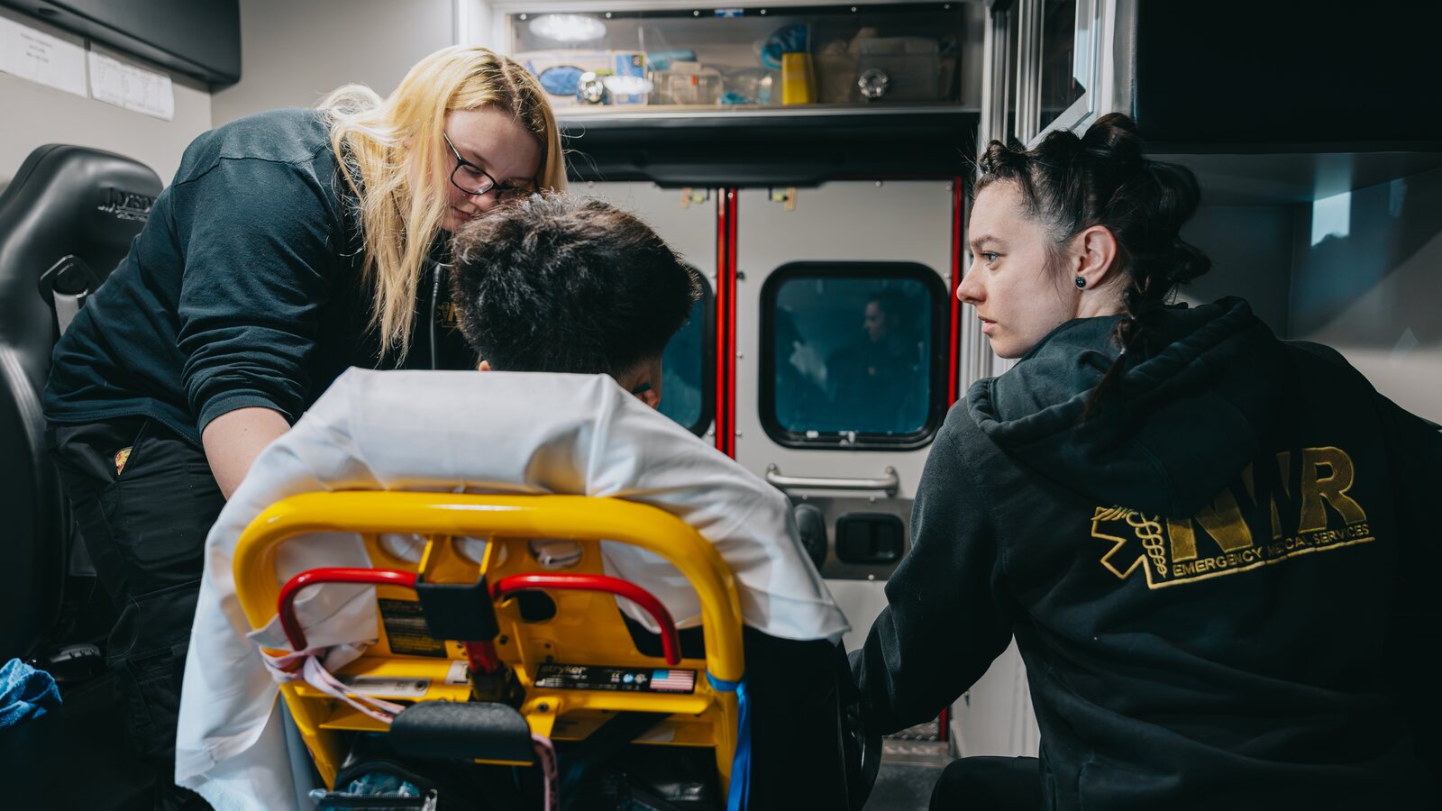 Two Northwest Rescue providers reviewing medical equipment together, illustrating the scope differences between EMT, paramedic, and critical care paramedic roles.