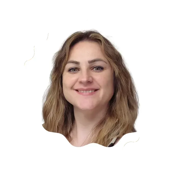 Smiling woman with wavy light brown hair and light eyes on a white background.