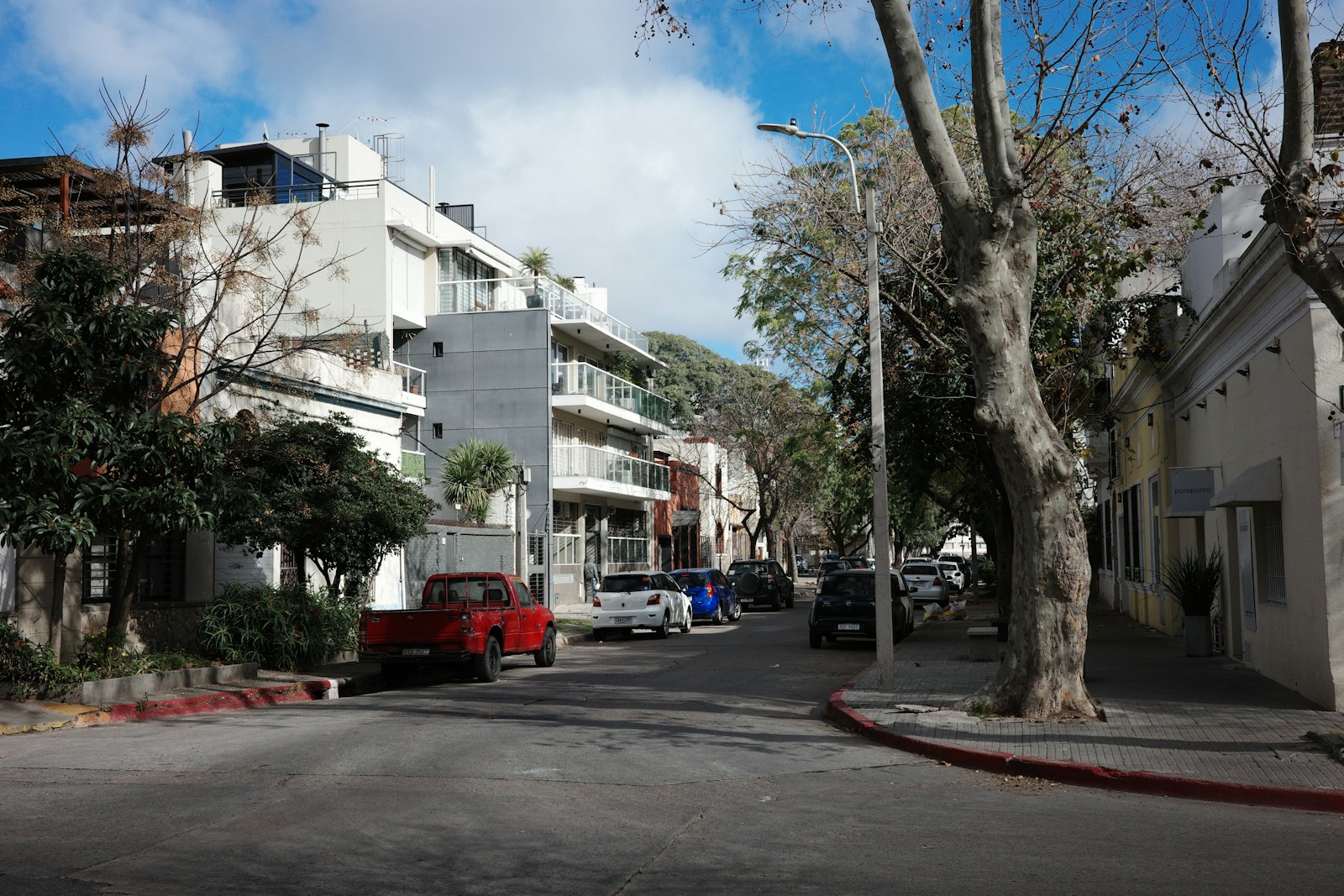 Street scene with cars and buildings on a sunny day.