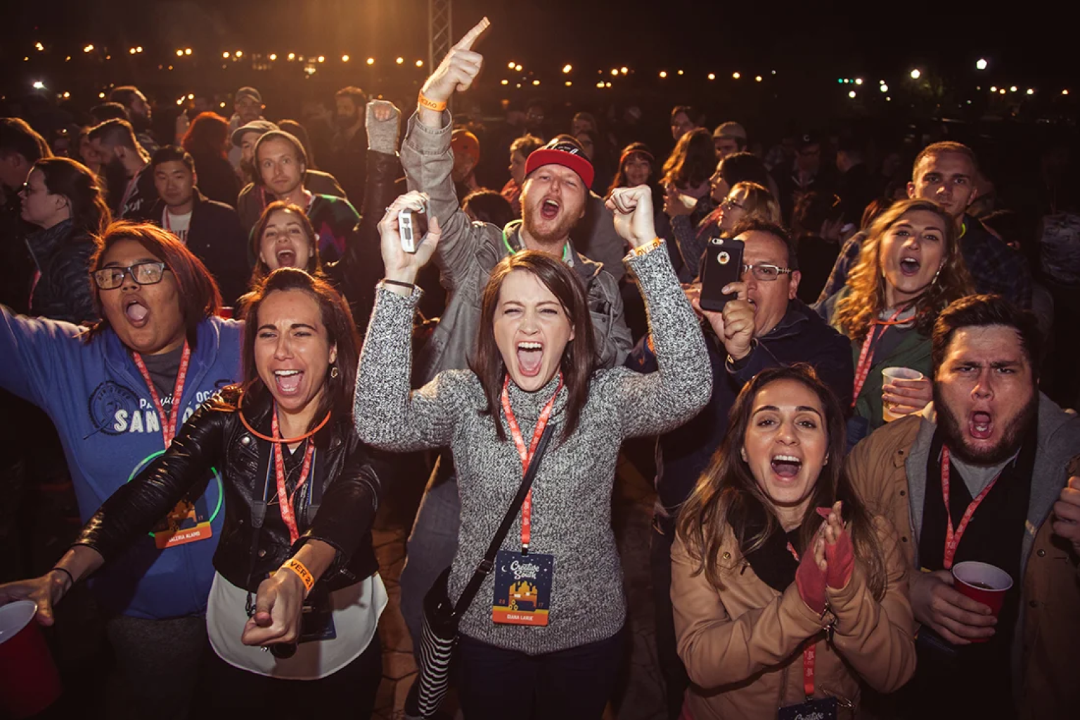 Excited crowd at a night party cheering with hands raised