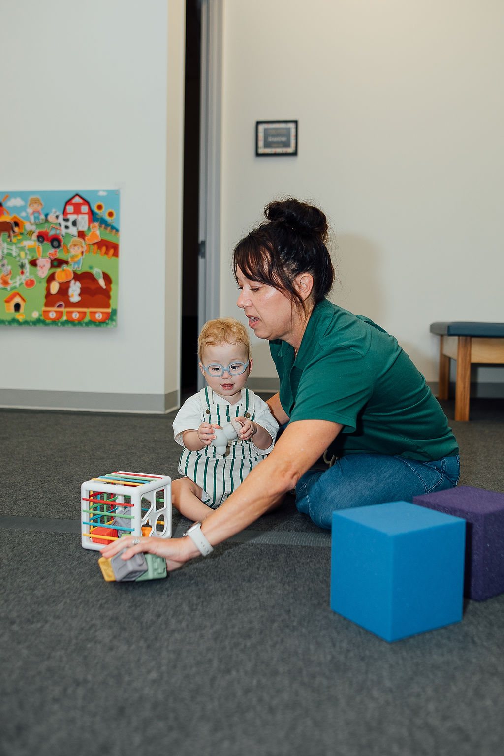 Baby reaching for soft blocks during floor play with an Oaklin Lane therapist
