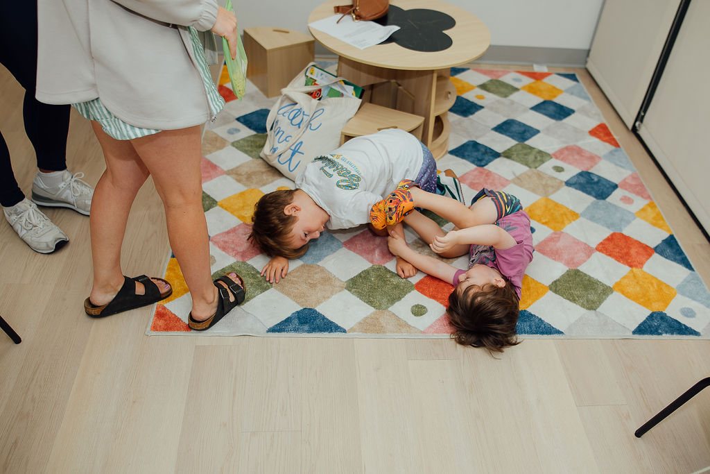 Two children doing floor movement games on a rug at Oaklin Lane