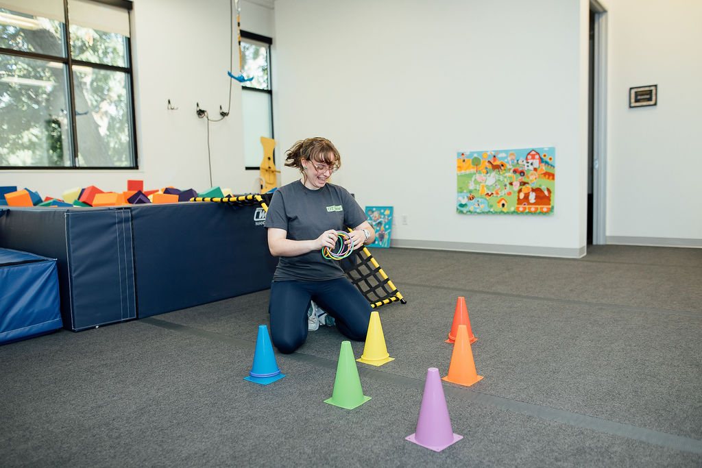 Oaklin Lane therapist setting up a cone obstacle route in the therapy gym