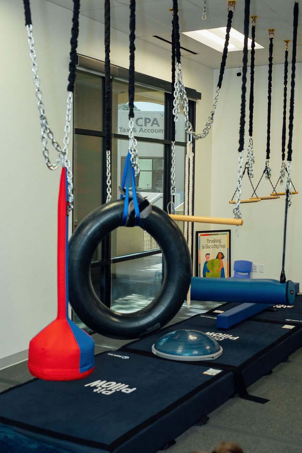 Tire swing, bolster swing, and crash mats in the Oaklin Lane sensory gym