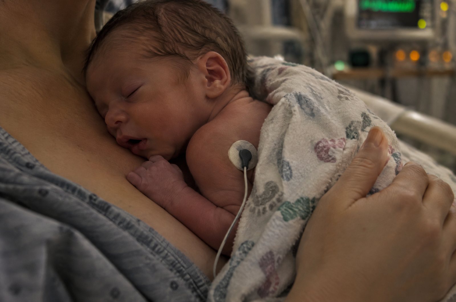 Parent holding a newborn skin to skin in a hospital NICU