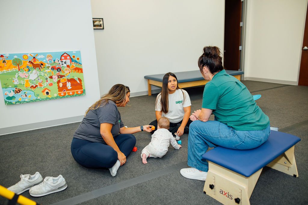 Baby on the floor with Oaklin Lane therapists during an infant session