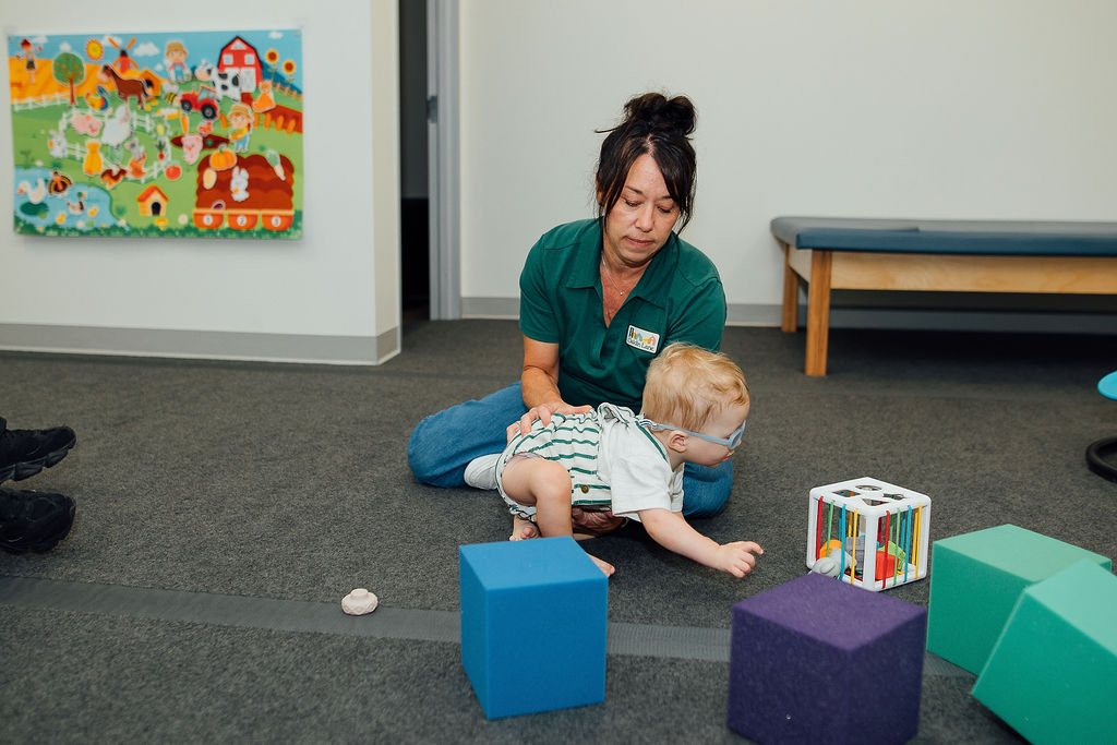 Baby playing on their tummy while an Oaklin Lane therapist coaches