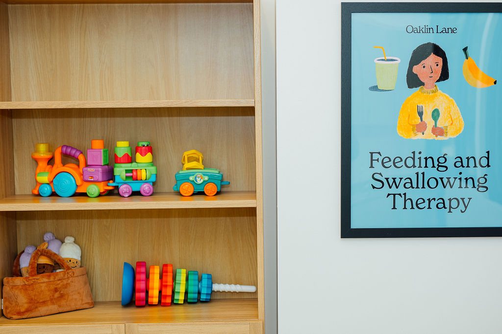 Toy shelf and a Feeding and Swallowing Therapy poster in an Oaklin Lane therapy room